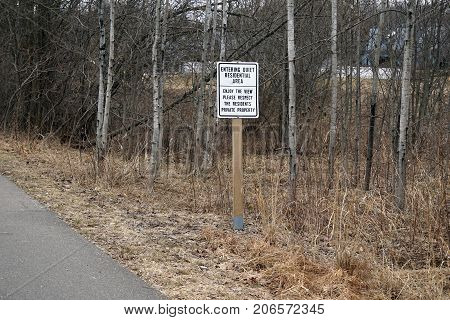 BAY VIEW, MICHIGAN / UNITED STATES - MARCH 30, 2017: A sign asks users of the Little Traverse Wheelway to be quiet in a residential area, and to respect the residents' private property.