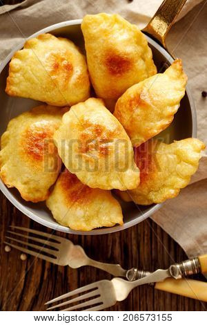 Baked dumplings stuffed with curd cheese and potatoes in a pan on wooden rustic table, nutritious and delicious vegetarian food,  Traditional Polish dish, top view
