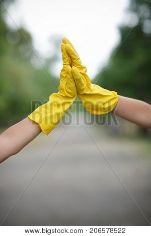 Team work of outdoors cleaning. Environmental protection. Closeup cropped portrait. Getting started cleaning. Yellow rubber cleaning gloves closeup. Workhouse concept. Helping team.