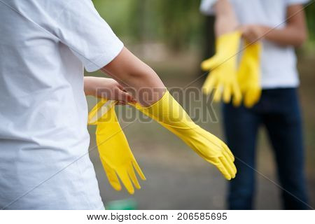 Team work of outdoors cleaning. Environmental protection. Closeup cropped portrait. Getting started cleaning. Yellow rubber cleaning gloves closeup. Workhouse concept. Helping team.