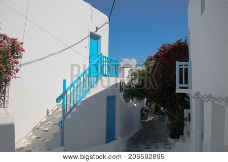 Beautiful White and Blue buildings in a street with flowering gardens on Island of Mykonos Greece