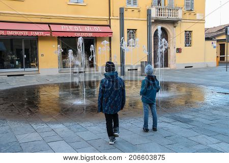 Vignola Italy - October 30 2016: Two boys looking at fountain in historic city centre. Emilia-Romagna Modena