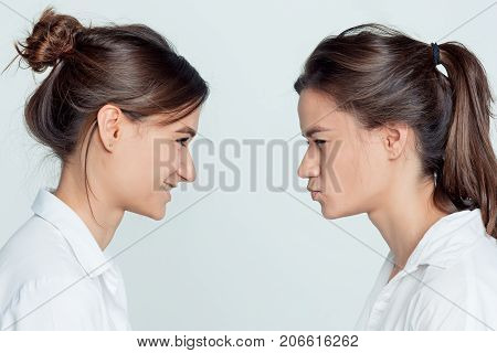 Studio profile portrait of young female twins sisters on gray