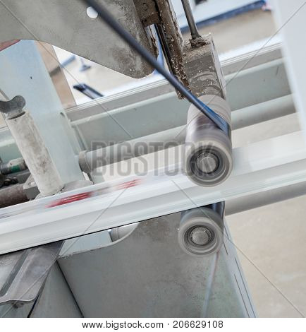 the machine glues the ribbon with the print on the profile. workshop for the production of PVC profile