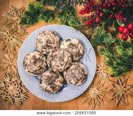 Christmas cookies with festive decoration. Plate with tasty New Year homemade sweets on wooden table. Gingerbread and christmas cookies with festive decor on wooden background.