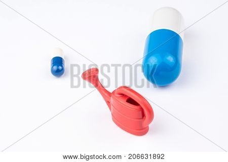 One Little Blue And White Pill, One Miniature Of Watering Can And One Big Capsule Looking Like A Pil