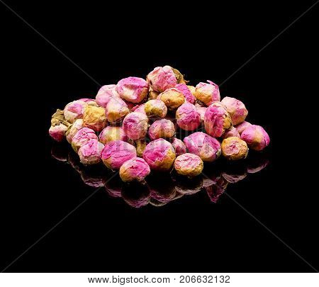 Dried peony flower buds. Chinese tea additive for brewing. On a black glossy background with real reflection. Flower tea