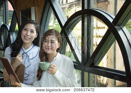 Asian business team discussing document at  coffee shop/Team work process. young business drinking a coffee and  looking at camera