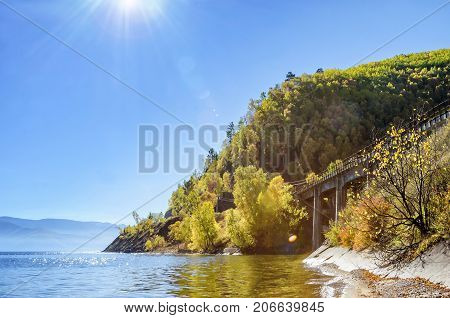 Rays of Sun in the nature with beautiful water, cost and stone bridge close to mountain, lake Baikal, Russia