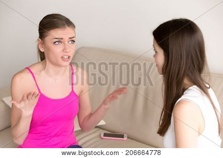 Frustrated young girl sitting on sofa at home, tells girlfriend about personal problems. Best friends chat about private matters. Sister carefully listens to her siblings rant without interrupting.