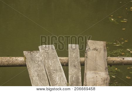 Wooden ramshackle walkway over old green pond