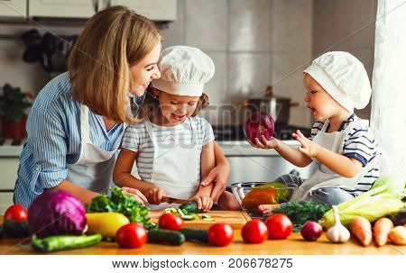 Healthy eating. Happy family mother and children prepares vegetable salad in kitchen