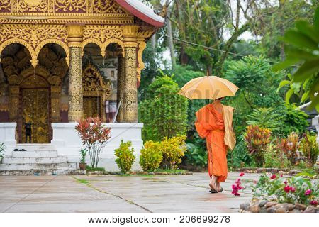 Monk with an umbrella on a city street Louangphabang Laos. Copy space for text