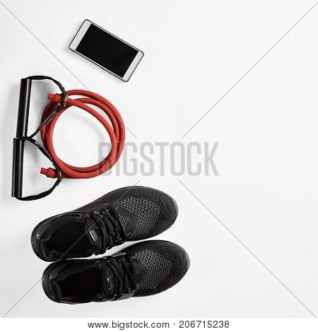 Athlete's male set with mobile phone, elastic expander and gymshoes, image with Square ratio