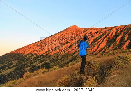Traveler is seeing and taking a photograph of Rinjani Summit at sunset time. Mountain Rinjani at Lombok, Indonesia.