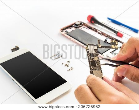 Close-up of technician hand clamping processor on smartphone logic board on smartphone component background with copy space
