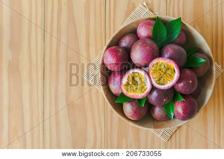 Passion fruit in wood bowl on wood table in top view flat lay with copy space for background or wallpaper. Ripe passion fruit so sweet and sour suitable make dessert. Passion fruit is tropical fruit. Passion fruit jam ready to served.