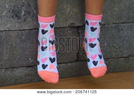 Girl feet in bright socks against a brick wall background