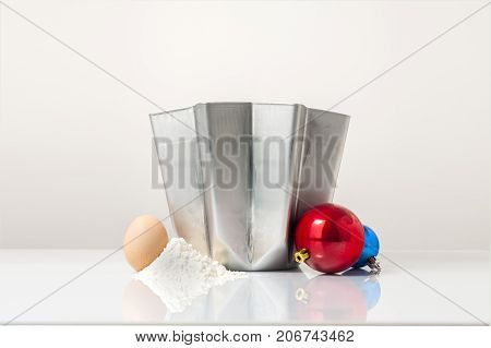 A cover shot for a pandoro recipe: a pandoro mold with egg flour and a couple of Christmas balls