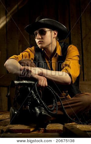 Cowboy with Black Leather Flogging Whip in his hand against wooden background