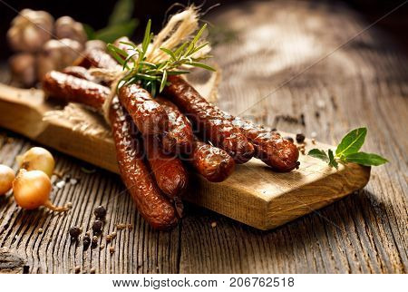 Kabanosy, polish sausages made of pork on a board with addition of fresh herbs and spices