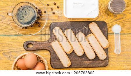 Image on top of table with savoyardi cookies, eggs, cream