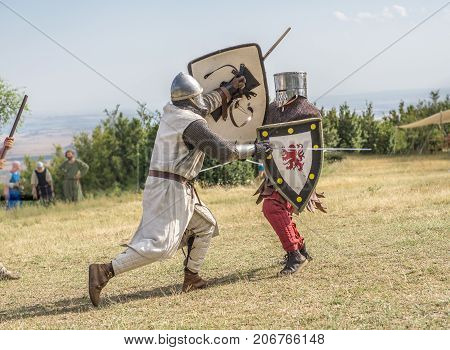 Medieval knight battle with swords and shields, reenactment with costumed characters and medieval armor with chainmail, helmet swords and shields. Medieval demonstration and recreation
