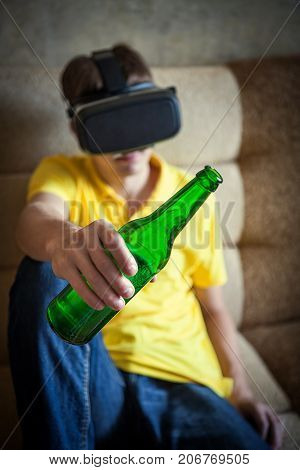 Man in VR Glasses hold Bottle of a Beer on the Sofa