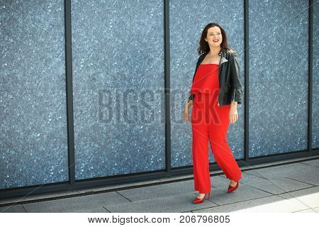 Beautiful overweight woman in red pantsuit walking on city street