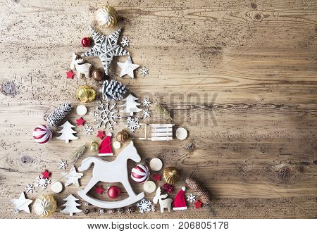 Christmas Decoration Forming Shape Of Christmas Tree. Decoration Like, Rocking Horse, Santa Hat, Fri Con And Christmas Ball Ornament. Aged Brown Wooden Background With Copy Space