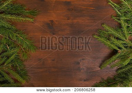 Flat lay chrismas rpattern larch and fir branches on the wood desk. Empty space for text.