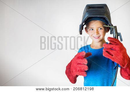 Happy little kid in welder mask and welding equipment. Welding equipment welding mask protective leather gloves welding electrodes. Fun concept. Child dreaming of future profession. Career choice.