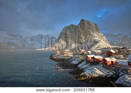 Hamnoy fishing village on Lofoten Islands, Norway with red rorbu houses. With falling snow blizzard in winter and rainbow