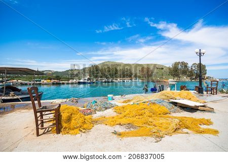 Nice aegean scene with fishing nets, old wooden chairs on the pier of the harbor of Georgioupolis, Chania, Crete, Greece, on April 11, 2017.
