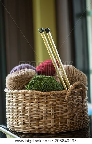 Balls of yarn in basket with knitting needles