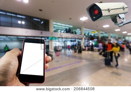 hand using smart phone monitoring and CCTV security indoor camera system operating in airport people transportation surveillance security and safety technology concept