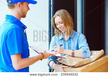 Smiling delivery man in blue uniform delivering parcel box to recipient - courier service concept. Smiling delivery man in blue uniform