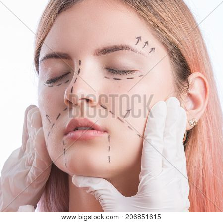 Young pretty girl with perforation lines on face and doctors hands. Isolated on white