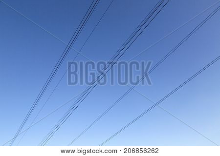 Electricity cables between pylons against a blue sky background
