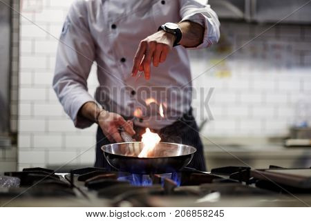 A man cooks cooking deep fryers in a kitchen fire. He gently fry the vegetables while cooking the dish.