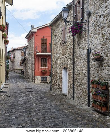 Frontino historic village in Montefeltro Pesaro Urbino Marches Italy). A street with the typical houses with plants and flowers
