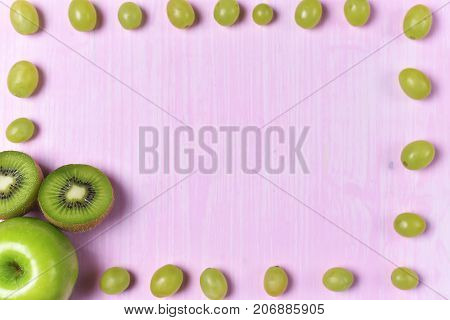 composition of kiwi and grape on a pink background