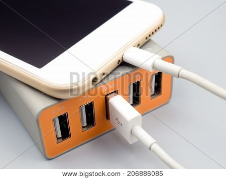 Close-up image of smart phone charging with multiport USB power adaptor on gray background Selective focus