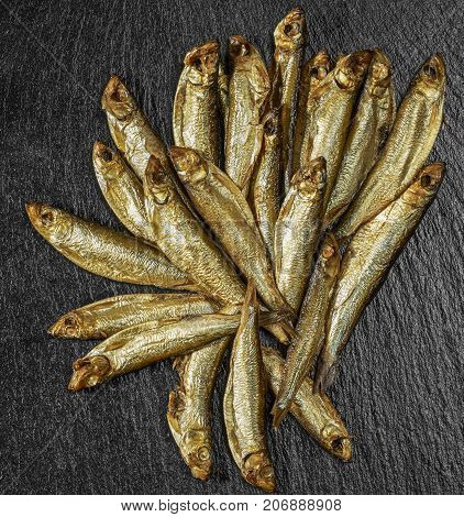 arrangement with lots of fresh smoked sprats on dark stone slab
