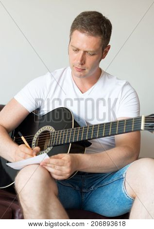 Handsome man compose a song on the guitar.