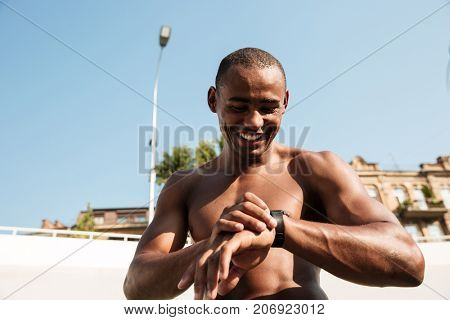 Half naked afro american musculary sports man checking time on wristwatch after workout