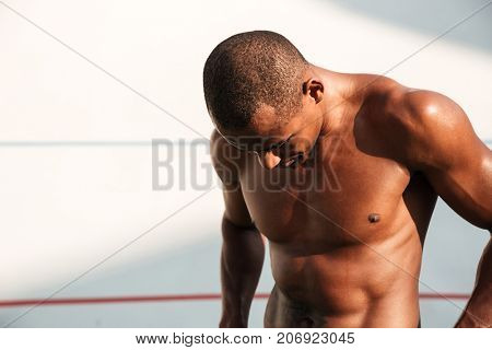 Close-up portrait of a sweaty handsome african sports man, resting after workout on stadium