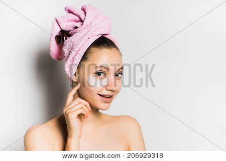 smiling girl with a towel on her head puts on the face foundation