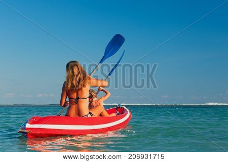Happy family - mother baby daughter have fun on boat walk. Woman and child paddling on kayak. Travel lifestyle parents with kids recreational activity and water sports on summer sea beach vacation.