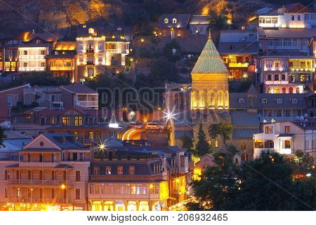 Amazing View of Saint George Church, famous colorful houses and balconies in Old Town in night Illumination during evening blue hour, Tbilisi, Georgia